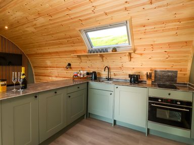 A kitchen with green cabinets a countertop sink oven and a window at Wren in Ingleton