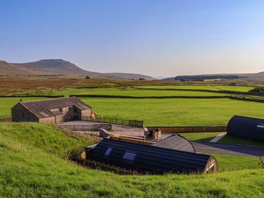 A countryside landscape with stone buildings and green fields at Wren in Ingleton