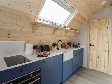 A kitchen with blue cabinets a white countertop a sink and a wooden door at Barn Owl in Chapel Le Dale near Ingleton