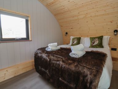 A bedroom with a double bed white towels on a dark brown throw and owl cushions at Barn Owl in Chapel Le Dale near Ingleton