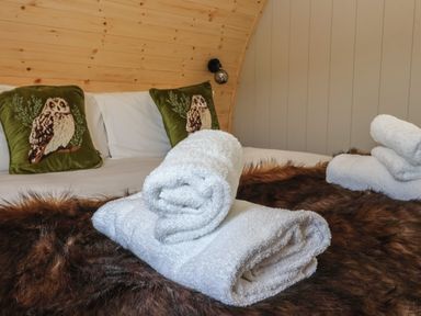 A bed with white towels on a brown fur blanket and owl pillows at Barn Owl in Chapel Le Dale near Ingleton
