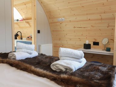 A bedroom with a bed covered in fur and white towels folded on top with a small desk and a mirror on the wall at Barn Owl in Chapel Le Dale near Ingleton