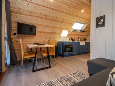 A kitchen and dining area with wooden walls blue cabinets and yellow chairs at Barn Owl in Chapel Le Dale near Ingleton