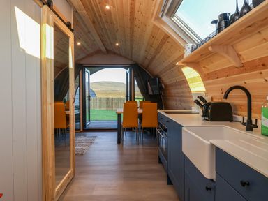 A kitchen and dining area with blue cabinets and wooden ceiling at Barn Owl in Chapel Le Dale near Ingleton