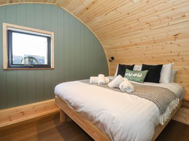 A bedroom with a wooden bed frame a white bed and a window at Curlew in Chapel Le Dale near Ingleton