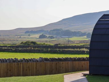 A grassy field with stone and wooden fences and hills in the background at Woodpecker in Chapel Le Dale near Ingleton