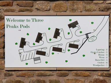 A site map showing layout and names of seven pods with a car park at Three Peaks Pods