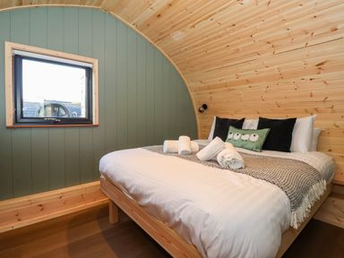 A bedroom with a double bed wooden walls and a window at Woodpecker in Chapel Le Dale near Ingleton