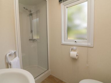 A bathroom with a shower enclosure a frosted window a toilet paper holder and a towel rack at 25 Manleigh Park Combe Martin