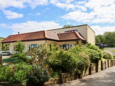 A house with a red tile roof and garden in front at 25 Manleigh Park in Combe Martin