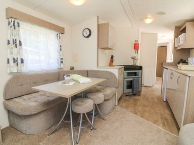 A kitchen and dining area with a corner bench seat and table with stools at 26 Manleigh Park in Combe Martin