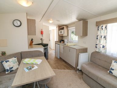 A kitchen with a dining table and seating area with cushions at 26 Manleigh Park in Combe Martin
