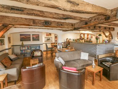 A living area with sofas and armchairs around small wooden tables and a bar counter with bottles and flowers at 26 Manleigh Park Combe Martin