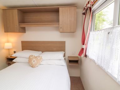 A bedroom with a bed and pillows with a lamp on a side table at 26 Manleigh Park in Combe Martin