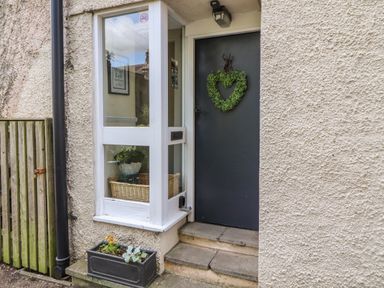 A gray front door with a heart-shaped wreath and a window with a basket inside at Belmont House in Bowness-On-Windermere