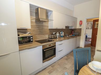 A kitchen with white cabinets wooden countertop built in oven toaster microwave and sink at Belmont House in Bowness-On-Windermere