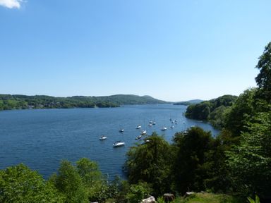 A lake with sailboats anchored near shore surrounded by trees and hills at Belmont House in Bowness-On-Windermere