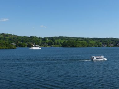 A lake with two white boats and green hills in the background at Belmont House in Bowness-On-Windermere