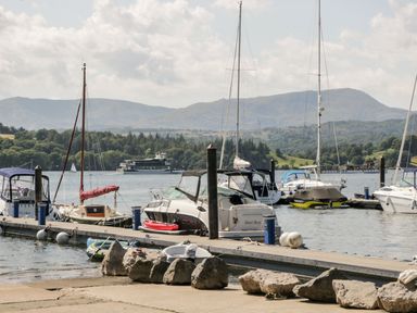 A marina with boats docked at a pier and hills in the background at Belmont House in Bowness-On-Windermere