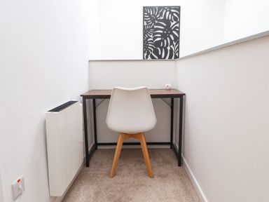 A small workspace with a wooden desk and a white chair with wooden legs at Hole in the Wall in Caernarfon