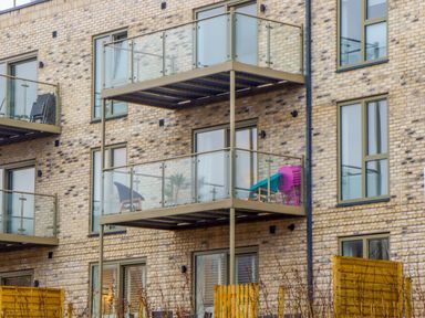 Balconies with glass railings on a brick apartment building with chairs and a table at Rolles Rainbow in Exmouth