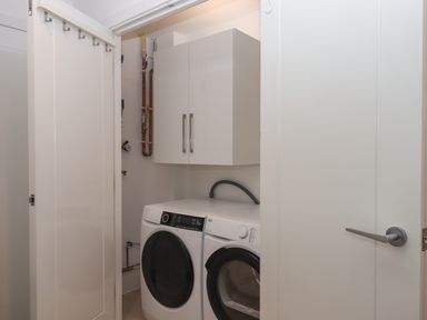 A laundry room with a washing machine dryer and wall cabinet at Rolles Rainbow in Exmouth