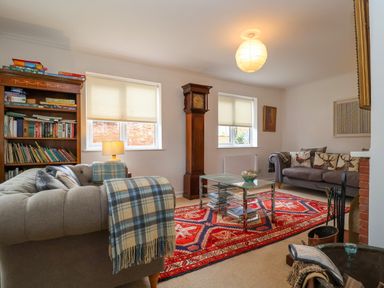 A living room with two sofas a red patterned rug a grandfather clock and a bookshelf at 1 Market Hill in Orford