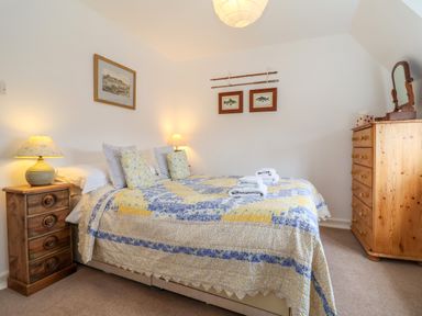 A bedroom with a double bed covered with a yellow and blue quilt at 1 Market Hill in Orford