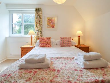 A bedroom with a double bed two bedside tables with lamps and folded towels at 1 Market Hill in Orford