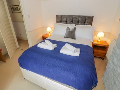 A bedroom with a double bed with a blue blanket and white towels at 4 Lansdown Cottages in Bourton-On-The-Water
