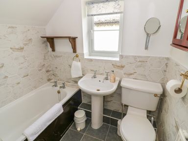 A bathroom with a bathtub sink toilet and a small window at 4 Lansdown Cottages in Bourton-On-The-Water