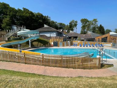 An outdoor swimming pool with a water slide and sun loungers at Lodge Nine in Finlake Holiday Park near Chudleigh