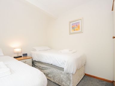 A bedroom with two beds a nightstand with a lamp and clock and a picture on the wall at Lodge Nine in Finlake Holiday Park near Chudleigh