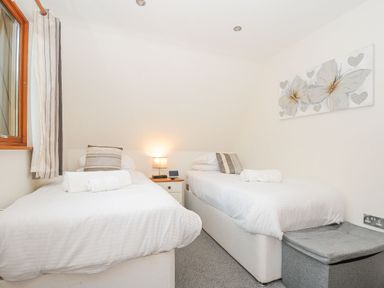 A bedroom with two single beds a lamp and a window at Lodge Nine in Finlake Holiday Park near Chudleigh
