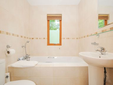 A bathroom with a bathtub a sink a toilet and a window at Lodge Nine in Finlake Holiday Park near Chudleigh