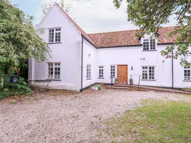 A white cottage with a tiled roof gravel driveway and green bins at White House Cottage in Little Snoring near Fakenham