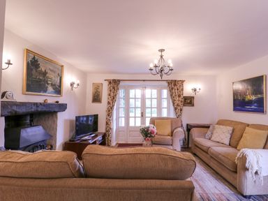 A living room with sofas a fireplace a television and paintings at White House Cottage in Little Snoring near Fakenham