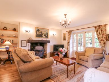 A living room with sofas and a fireplace a coffee table with flowers and a television at White House Cottage in Little Snoring near Fakenham