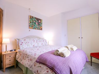 A bedroom with a double bed floral bedding bedside table lamps and rolled towels on the bed at White House Cottage in Little Snoring near Fakenham