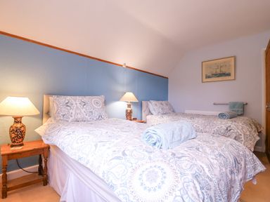A bedroom with two single beds bedside tables lamps and a painting on the wall at White House Cottage in Little Snoring near Fakenham