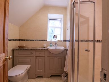 A bathroom with a toilet sink cabinets a shower and a small window at White House Cottage in Little Snoring near Fakenham