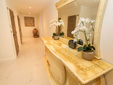 A hallway with a large mirror above a marble console table with a potted plant and vase at 17 Cliff Edge in Newquay