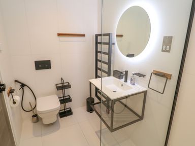 A bathroom with a wall-mounted toilet and a white sink with a black frame at 17 Cliff Edge in Newquay