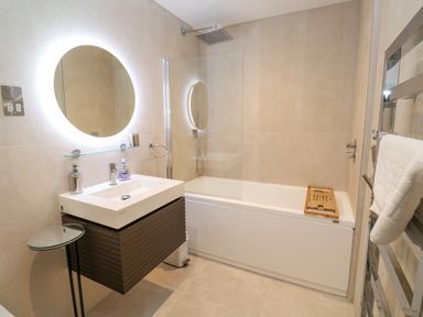 A bathroom with a bathtub a sink with mirror and a towel rack at 17 Cliff Edge in Newquay