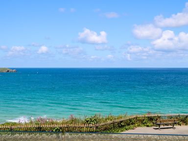 A view of the ocean with a bench and flowers near a fence at 17 Cliff Edge in Newquay