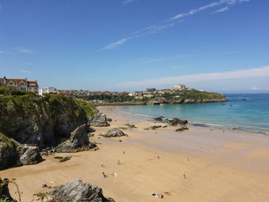 A sandy beach with people and rocks near houses and a coastal town at 17 Cliff Edge in Newquay