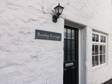 A white textured wall with a black door and window and a sign that says Rosehip Cottage at Rose Hip Cottage in Bellingham