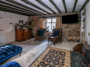 A living room with two leather armchairs near a window and a wooden cabinet at Rose Hip Cottage in Bellingham