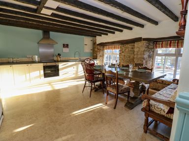 A kitchen with wooden beams stone walls dining table and chairs at Rose Hip Cottage in Bellingham