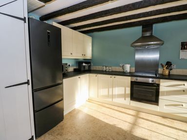 A kitchen with black refrigerator white cabinets oven and range hood at Rose Hip Cottage in Bellingham